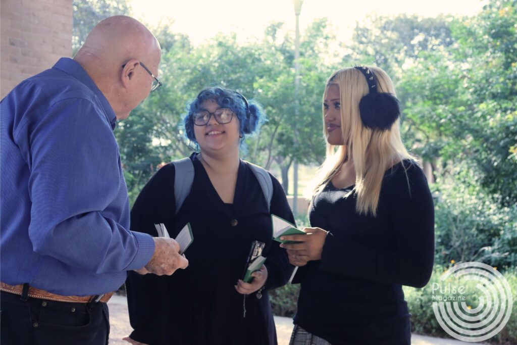 Retired teacher Virgil Croeker with Gideon International handing bibles to Karyna Hernandez, a marketing freshman and Blanca Reyes, an integrated health science freshman on Edinburg campus Nov. 6. Mikaela Lagunes/ Pulse.