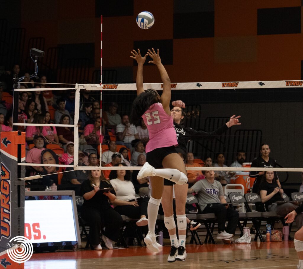 Middle blocker Shylah Totten reaches above the net and blocks the ball.